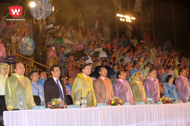 Các lãnh đạo, quan chức mặc áo mưa trong lễ khai mạc