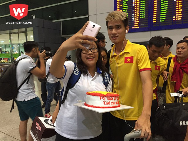 Trung vệ Đinh Tiến Thành được fan nữ này tặng bánh đầu tiên và chụp hình. Ảnh: Thái Hải.
