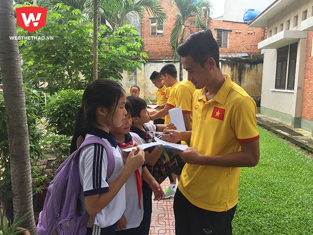 Tiền vệ Vũ Minh Tuấn vừa ký tặng vừa hỏi thăm hoàn cảnh của một bé gái.