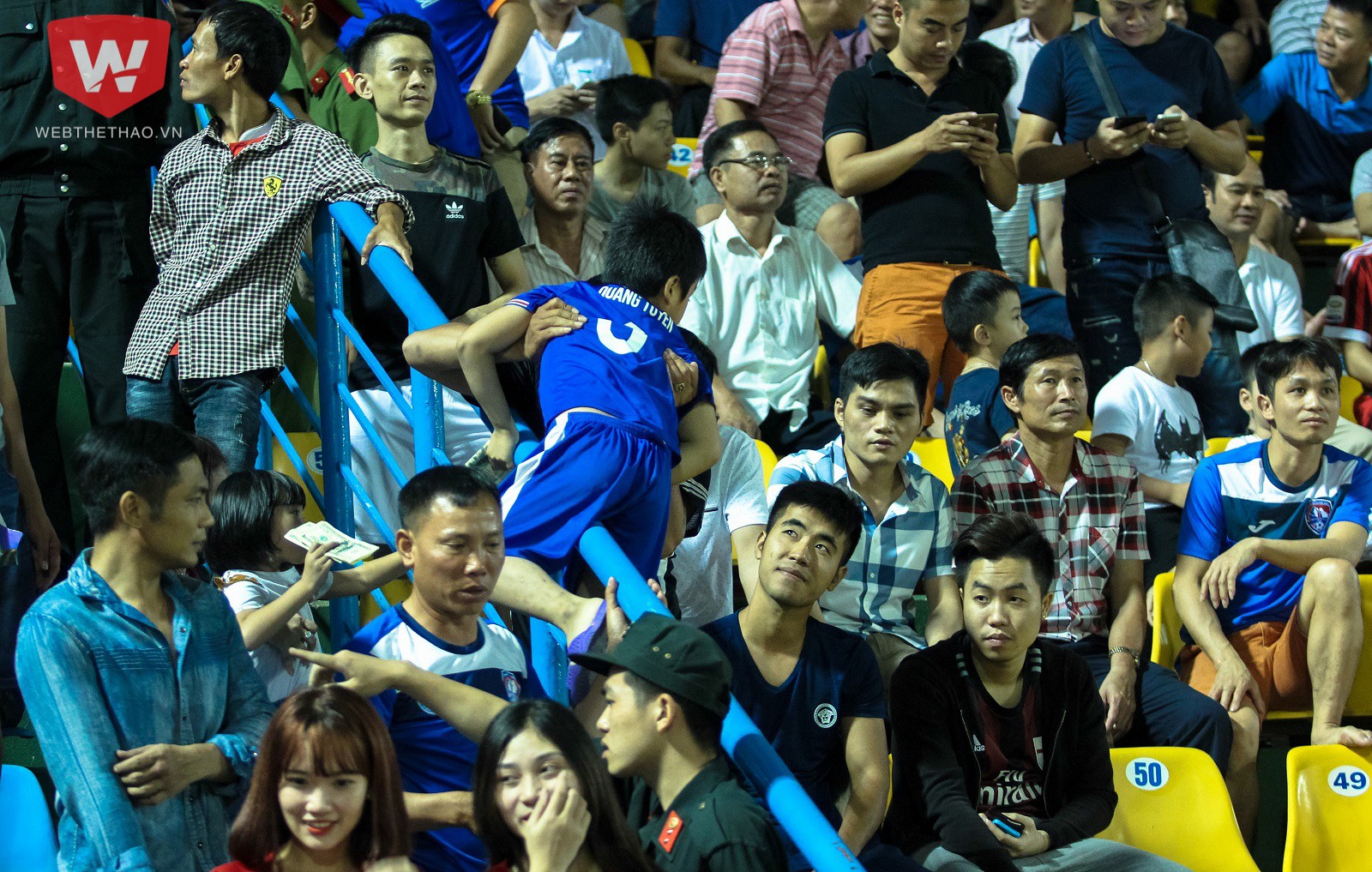 Một cổ động viên Than Quảng Ninh ''lạc lối'' vào đám đông cổ động viên áo đỏ đã phải bế con rời đi ngay khi hiệp 1 kết thúc. Ảnh: Trung Thu.
