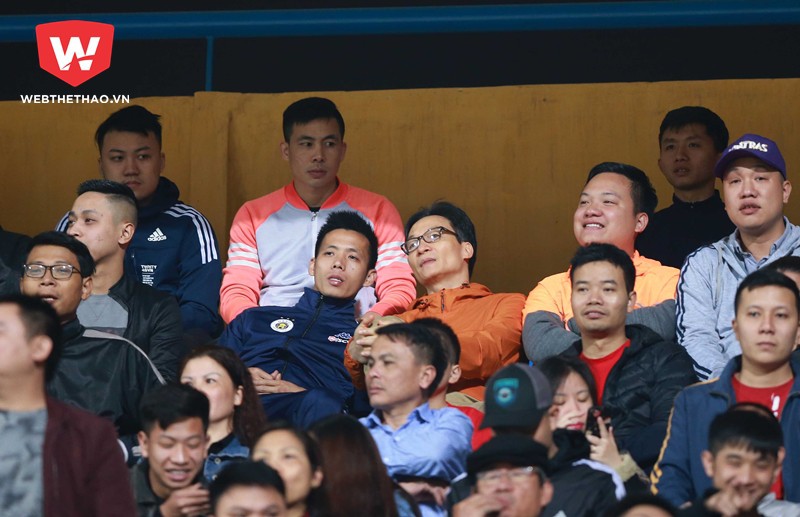 Phó Thủ tướng Vũ Đức Đam (áo cam) ngồi cùng tiền đạo Nguyễn Văn Quyết theo dõi trận đấu giữa Hà Nội FC và Hải Phòng FC. Hình ảnh: Hải Đăng.
