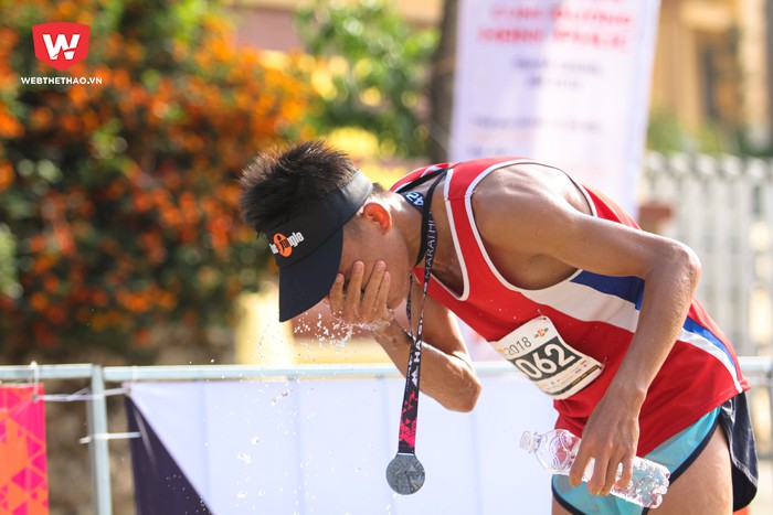 VĐV Nguyễn Quốc Dũng, người đầu tiên về đích ở cự ly marathon 42km. Khi về đích, anh ngay lập tức táp nước vào mặt để tỉnh táo hơn và giảm bớt nóng bức. Hình ảnh: Trung Thu.