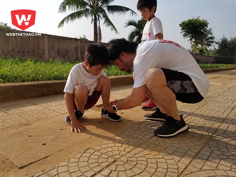 Anh Đỗ Minh (phải) buộc giày cho con tại Ironkids 2017.