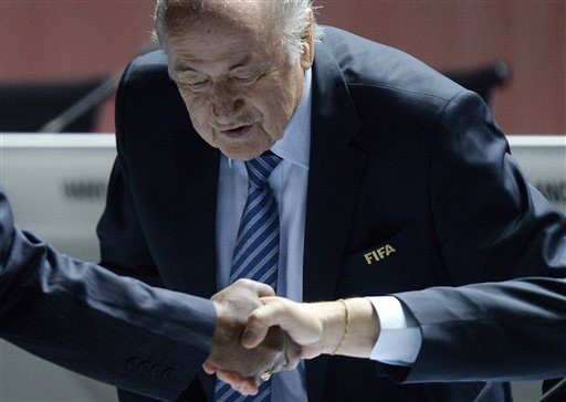 FIFA president Sepp Blatter takes a seat as people shake hands in front of him during the 65th FIFA Congress held at the Hallenstadion in Zurich, Switzerland, Friday, May 29, 2015, where he will run for re-election as FIFA head. (Walter Bieri/Keystone via AP)